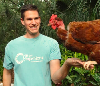Kenny Coogan wearing a green shirt with a naked necked chicken perched on his hand
